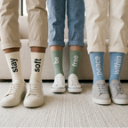 Three people wearing socks with motivational phrases on a carpeted floor.